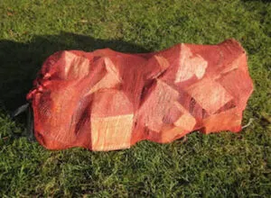 Bundle of red firewood logs laid out on grass | TreesUK